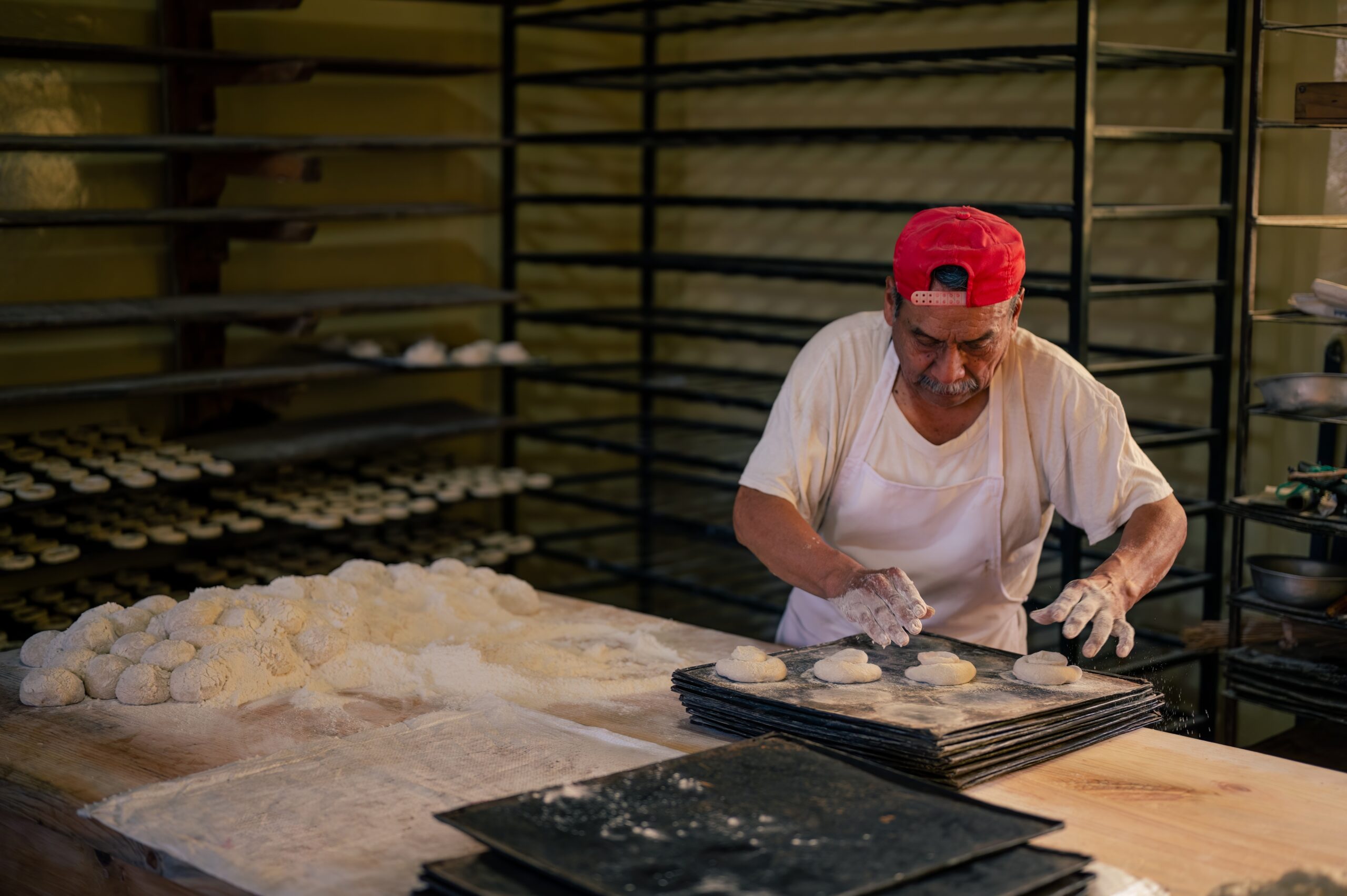 Latino,Baker,In,His,Artisanal,Bakery,,Making,Bread,To,Sell. Tax time with wooden alphabet blocks, red alarm clock, calculator and pen on 1040 tax form background